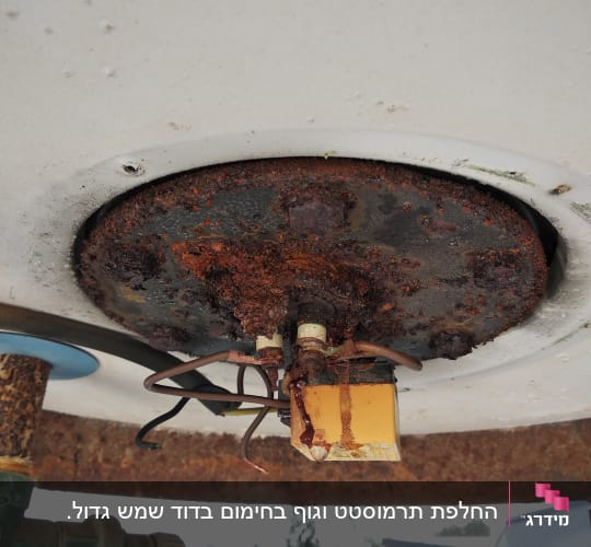 חלק תחתון של דוד שמש עם חלודה וחוטים חשמליים